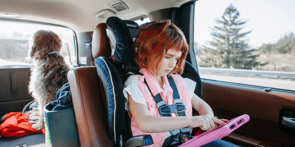 A child in a carseat using a tablet and following screen time rules set by a parent