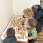 Center Child Care Provider in action with kids playing in a sandbox