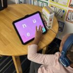 Center Child Care Provider with child playing on tablet